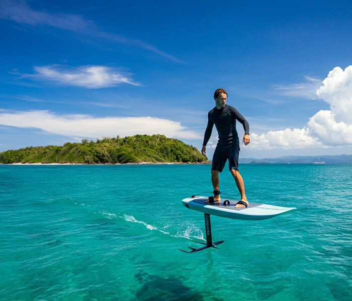 E-foil electric surfboard above turquoise water near tropical island, Koh Samui